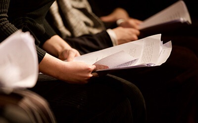 Participants holding scripts during a rehearsal, indicating a preparation for a performance or collaborative project.