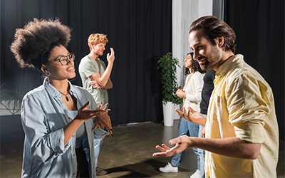 A diverse group of people engage in animated conversation in a modern studio, highlighting teamwork and communication in a collaborative environment.
