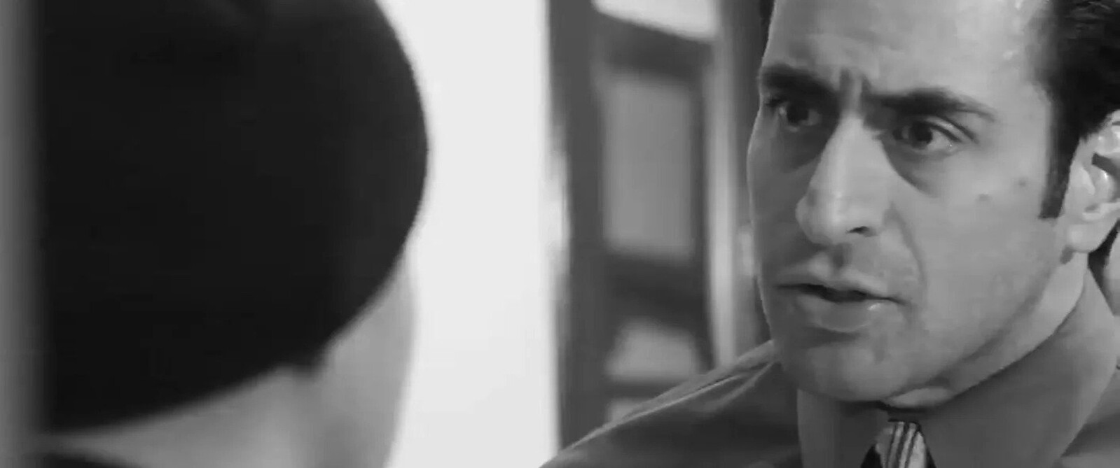 Intense confrontation between two men in black and white, focusing on the expressive face of one man, conveying drama and tension.