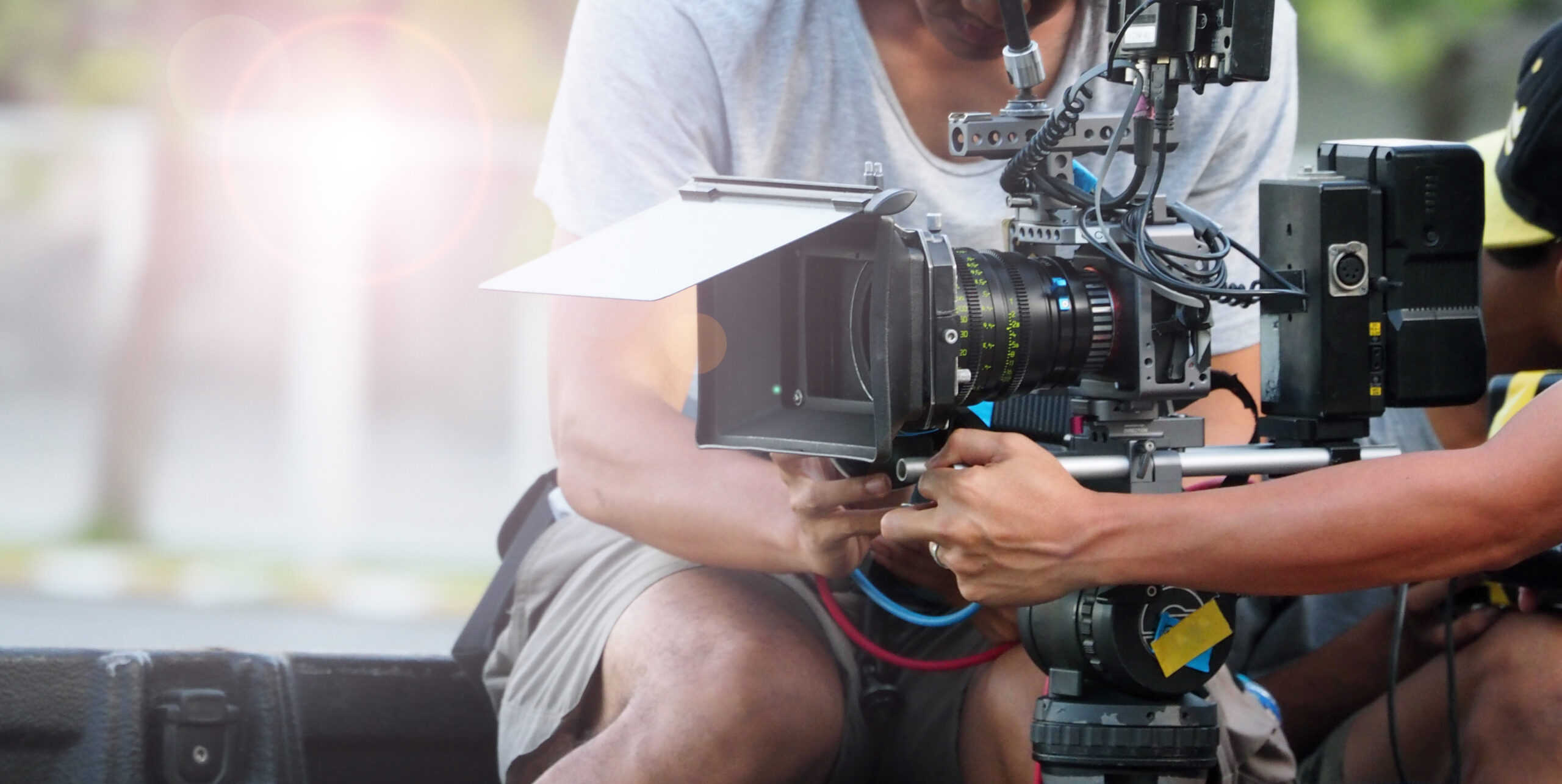 A film crew member adjusts a professional camera setup, showcasing the intricate equipment used in filmmaking. The image highlights the technical aspects of production.